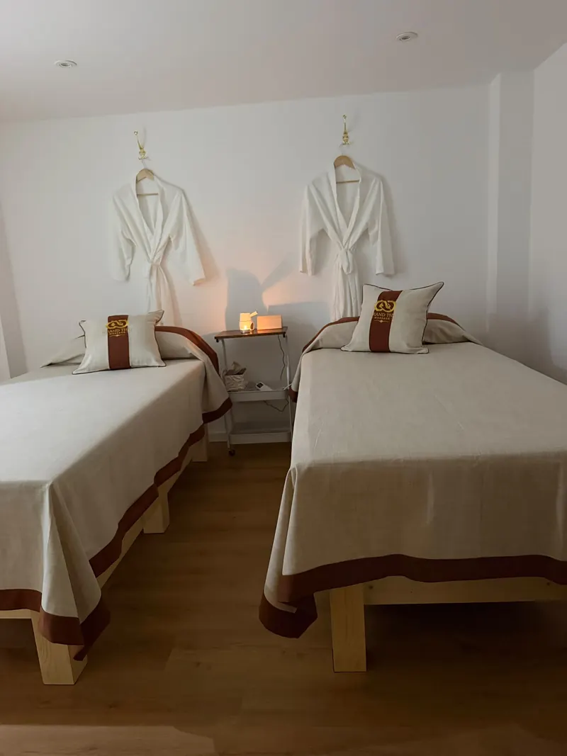 Behandlungsraum mit zwei Massageliegen und Bademänteln